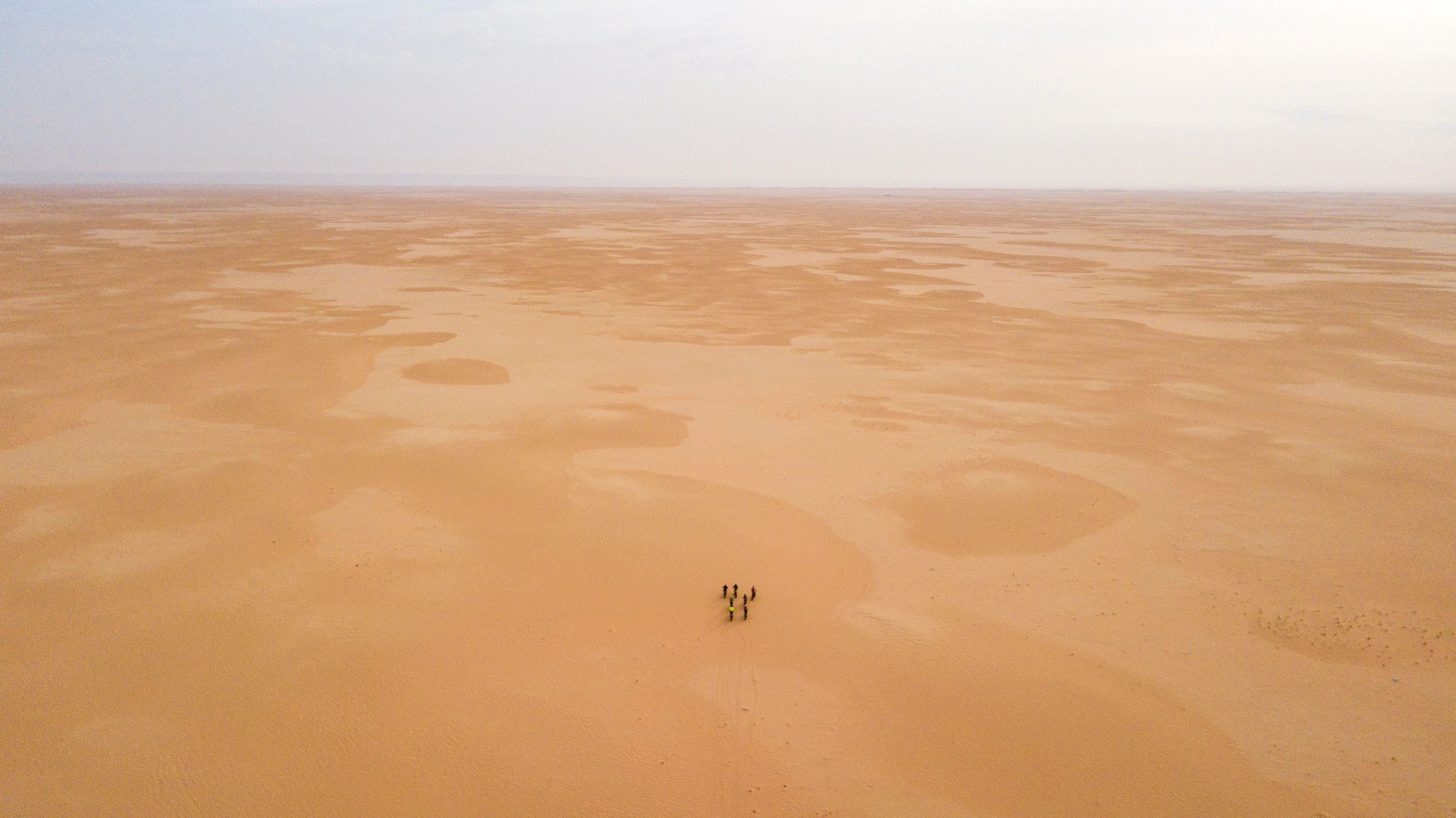 Travelers walking through a dramatic desert landscape